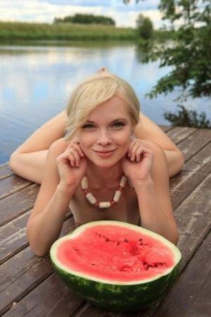Beautiful blonde Feeona eats a watermelon while posing naked on lakeside dock on leaks.pics
